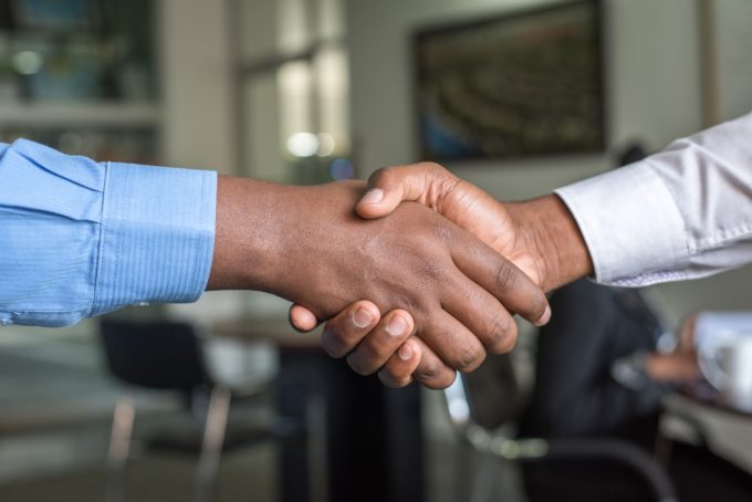 A handshake between two men in business clothes. Only the hands and arms are visible. 